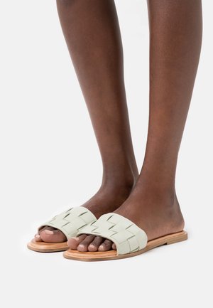 Lysegrønne vævede slip-på sandaler med åbne tæer, flade træsåler og et tekstureret overdel-design. Glat overflade og afslappet stil.