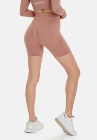 Hoge taille, lichtroze, rekbare shorts met textuurpanelen. Gecombineerd met witte sneakers met reflecterende accenten en een gestructureerde zool.