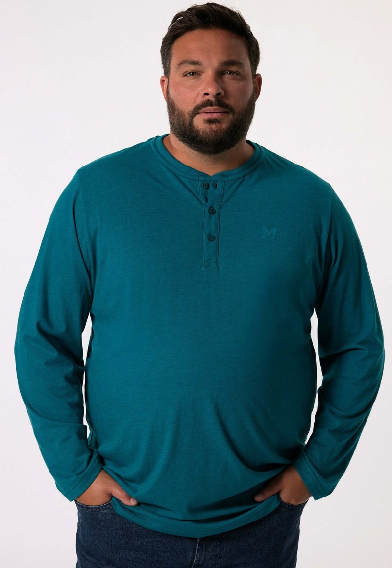 Tyrkysová dlouhá košile s výstřihem henley, obsahující tři knoflíky a embosované logo na hrudi. Měkká, hladká textilie.