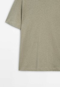 T-shirt beige à manches courtes avec un design simple, uni, et des coutures visibles à l'ourlet et à la manche.