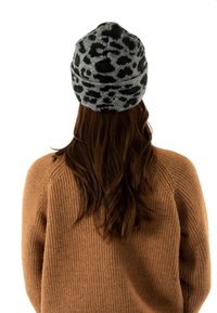 Gorro de punto gris con estampado de leopardo verde; textura suave, diseño ligeramente caído. Se lleva con un suéter grueso beige.