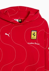 Rode hoodie met witte stiksels, voorzien van een Puma-logo en een Scuderia Ferrari-embleem. Gemaakt van gladde stof, met een ruime capuchon.