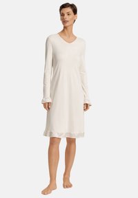 Vestito da notte a maniche lunghe, color crema, con scollatura a V e orlo arricciato. Realizzato in tessuto morbido, presenta una vestibilità comoda e polsini arricciati.