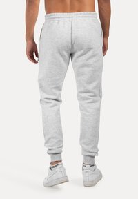 Grijze taps toelopende sweatpants met een elastische tailleband, zijzakken en ribgebreide boorden, gecombineerd met witte sneakers. Klassiek casual ontwerp.