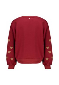 Sweatshirt rouge à manches longues avec des motifs de coeurs dorés le long des bras extérieurs. Il a un col rond et un ourlet côtelé.