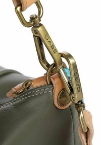 Borsa in pelle verde oliva con angoli in pelle marrone chiaro, caratterizzata da accessori in ottone e un logo del marchio visibile su un'etichetta circolare.