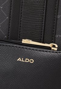 Černá texturovaná kabelka z umělé kůže se zlatým zipem, na přední straně značka "ALDO" vyražená zlatě.