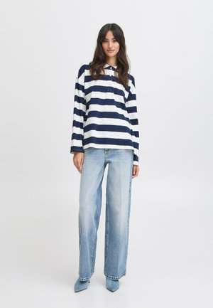 Long-sleeve navy and white striped shirt with a collar, paired with light blue high-waisted straight-leg jeans and matching heeled shoes.