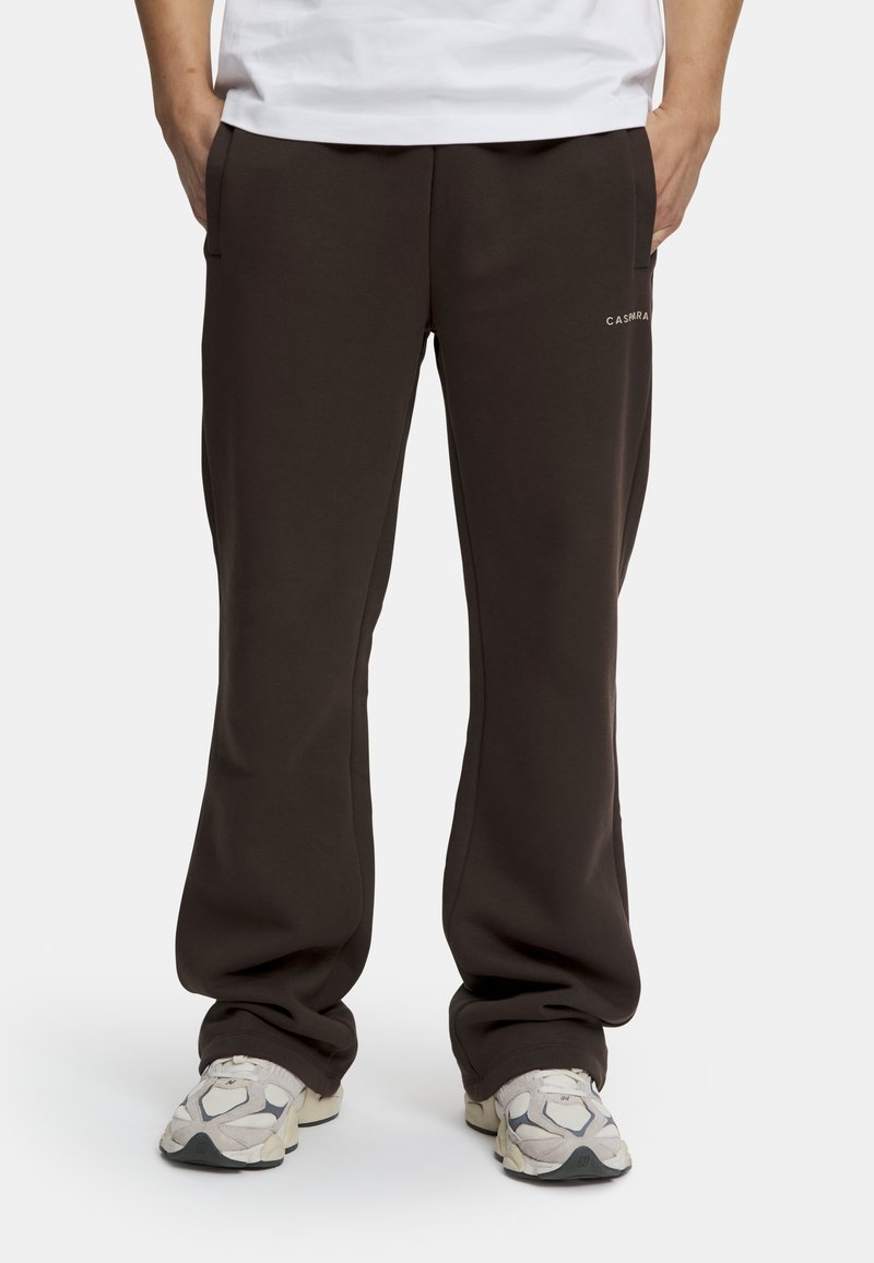 Bruna, avslappnade sweatpants med sidofickor och en diskret logotyp på vänster sida. Tillverkade av mjukt, texturerat tyg.