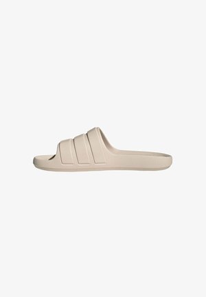 Sandalia beige tipo slip-on con tres tiras horizontales anchas y suela plana, diseñada para uso casual.