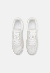 Weiße Sneakers mit grauen Wildlederdetails, perforierter Zehenbox und weißen Schnürsenkeln. Glattes Leder und Textilmaterialien durchgehend im Design.