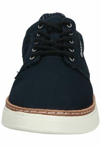 Scarpe da tela blu navy con lacci neri, suola in gomma e dettagli beige. Presentano cuciture decorative e una punta rotonda.