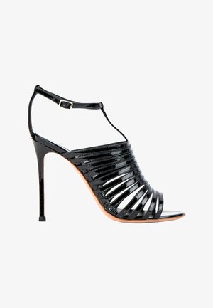 Sandale noire à talons hauts avec plusieurs fines brides, bout ouvert et bride à boucle à la cheville sur fond blanc.
