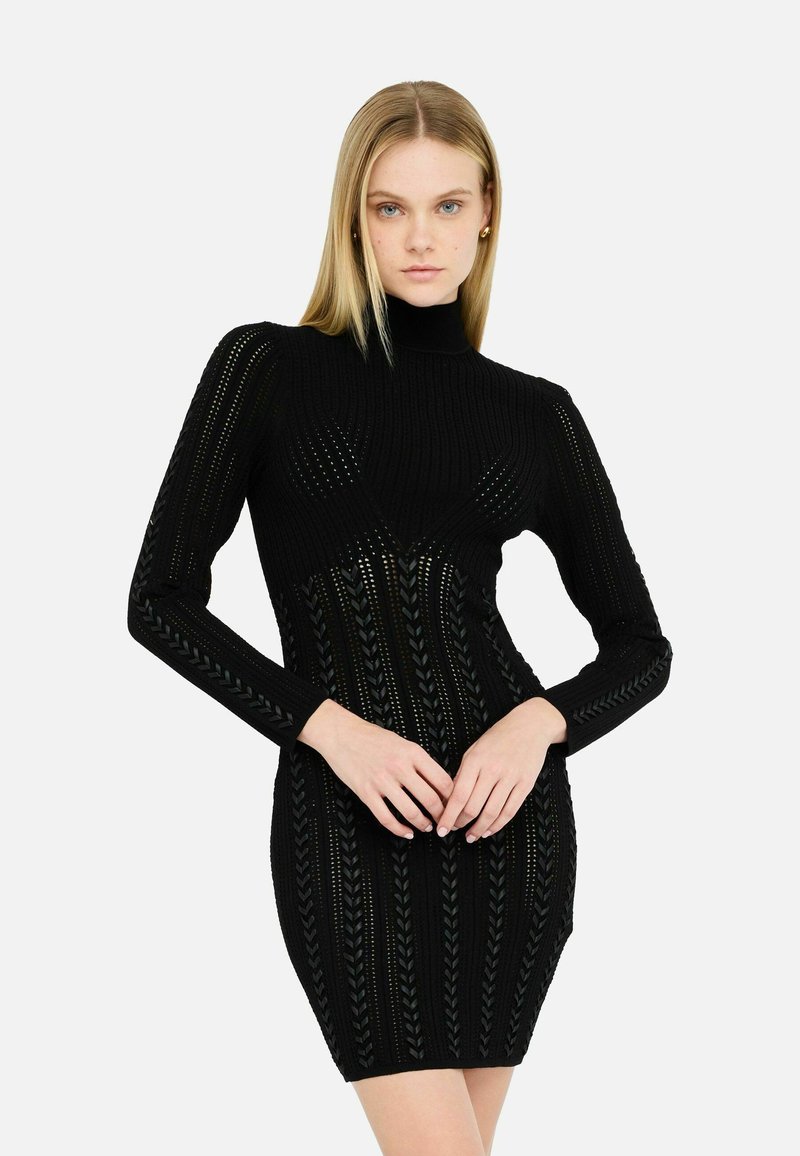 Schwarzes geripptes Strickkleid mit langen Ärmeln, hohem Kragen und einem strukturierten Muster mit vertikalen Linien und Blattmotiven.