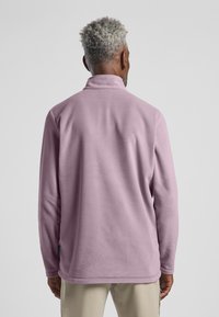 Fleece-Pullover in pastelllila, mit hohem Kragen und langen Ärmeln. Glatte Textur mit lockerer Passform und Säumendetails.