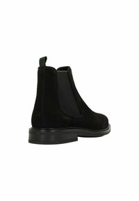 Zwarte suède Chelsea-boots met elastische zijkanten, een trekband en een platte zwarte zool. Glad textuur met een minimalistisch ontwerp.