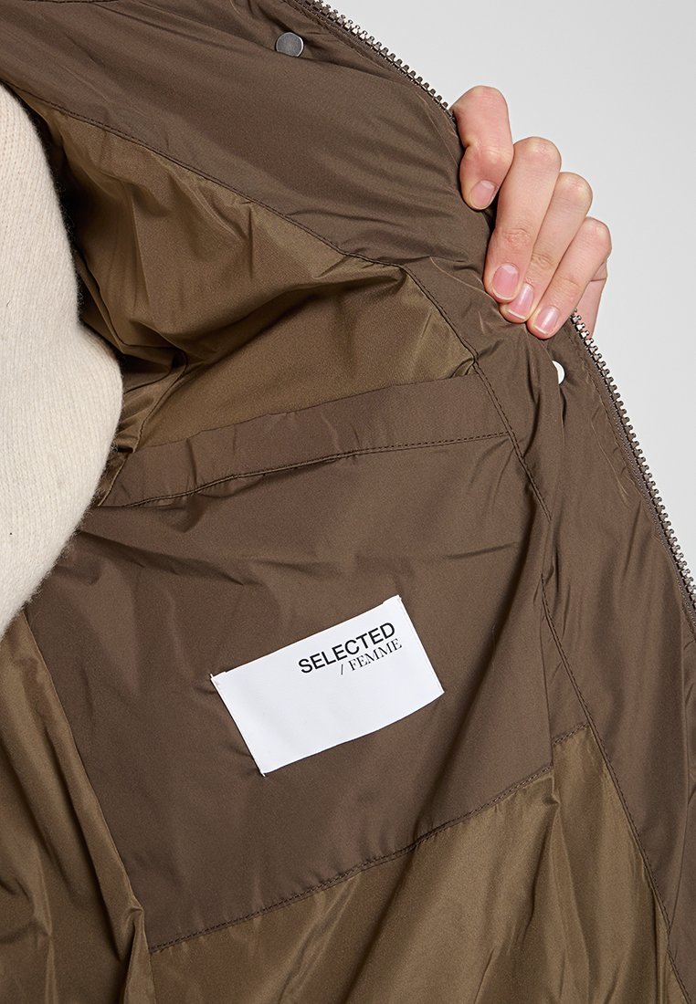 Giacca isolante marrone con una texture lucida, dotata di una tasca interna e un'etichetta con la scritta "SELECTED / FEMME." Dettagli in zip argentati visibili.