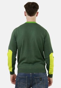 Maglione verde lavorato a maglia con colletto tondo, caratterizzato da vivaci dettagli gialli sui gomiti e sui polsini. Tessuto liscio, design casual.