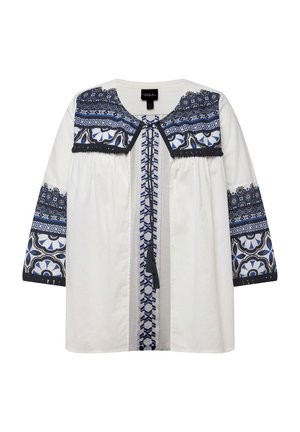 Blusa blanca con patrones florales y geométricos bordados en azul en el cuello y las mangas, con un detalle de lazo en la parte frontal y mangas de tres cuartos.
