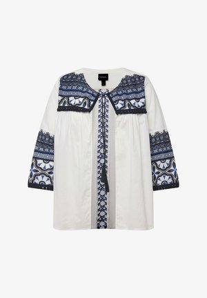 Blusa blanca con patrones florales y geométricos bordados en azul en el cuello y las mangas, con un detalle de lazo en la parte frontal y mangas de tres cuartos.