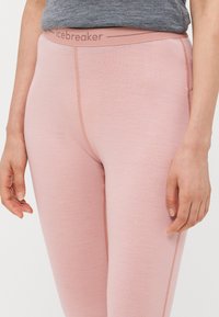 Lyserosa leggings med en jevn tekstur, med en bred midjebånd merket "icebreaker" og subtile sømdetaljer på sidene.