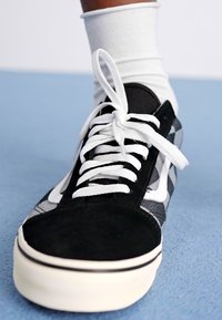 Black and gray patterned sneaker with lace-up design, suede and canvas materials, featuring white laces and a white rubber sole.