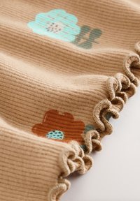 Brunt ribbet stof med turkis og orange blomsterprint, med en flæsekanter, der tilføjer tekstur og detaljer.