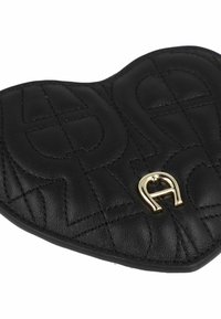 Cartera de cuero negro en forma de corazón con patrón acolchado, adornada con un acento dorado. Textura suave con detalles de costura.