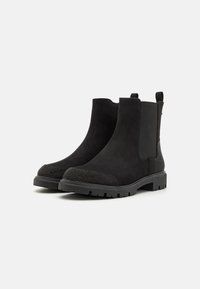 Bottines en daim noir à panneaux latéraux élastiques, bout texturé noir et semelle en caoutchouc robuste ; design minimaliste avec des accents contrastés.