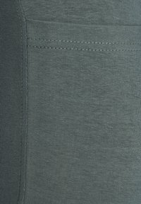 Dark green stretchy fabric, fine ribbed texture, flat seams, and a slightly padded section for comfort. Features a minimalistic design.