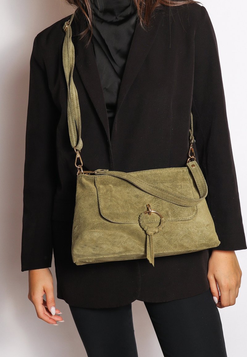 Borsa a tracolla in suede verde oliva con pattina anteriore, dettaglio hardware circolare e tracolla testurizzata. Superficie liscia e forma morbida.