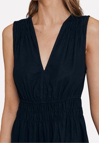 Marineblaues ärmelloses Kleid mit tiefem V-Ausschnitt, gerafften Details an den Schultern und elastischem Bund für eine taillierte Silhouette. Weicher Stofftexture.