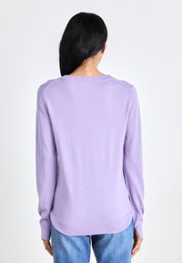 Sweater lilás de mangas longas com decote redondo, textura suave, punhos e bainha canelados, e parte de trás ligeiramente alongada.