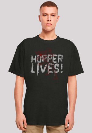 Black cotton t-shirt featuring a graphic design with the text "HOPPER LIVES!" in distressed white and red. Loose fit with short sleeves.