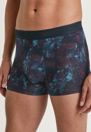 Herren-Boxershorts in einem dunklen kastanienbraunen und blauen abstrakten Muster, mit einem schwarzen Bund, der mit "CALIDA"-Markierung versehen ist, aus weichem Stoff gefertigt.