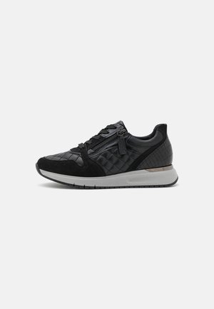 Czarny pikowany sneaker ze skórzanymi i zamszowymi detalami, sznurowaniem z przodu, zamkiem błyskawicznym po boku oraz białą amortyzowaną podeszwą na jednolitym tle.