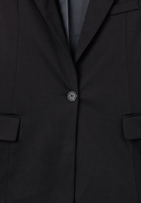 Blazer nero in tessuto liscio, chiusura con un bottone, rever a lancia e due tasche con patta. Design pulito e sartoriale.