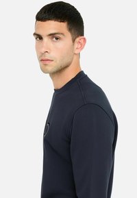 Marineblaue Rundhals-Sweatshirt aus strukturiertem Material, mit einem dezenten Logo auf der Brust und enganliegenden langen Ärmeln.