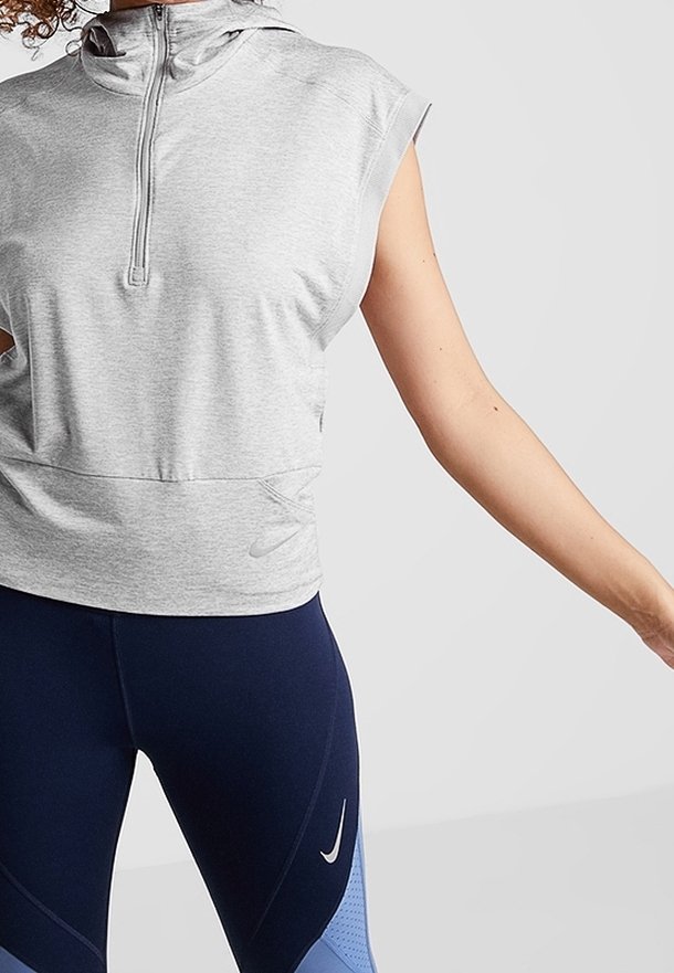 Gray sleeveless hoodie with a zippered neck, features a subtle Nike logo. Paired with navy leggings with blue accents and geometric patterns.