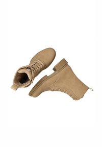 Stivaletti alla caviglia color beige realizzati in un materiale simile alla pelle scamosciata, con punta arrotondata, lacci laterali e un tacco testurizzato con una linguetta per indossarli facilmente.