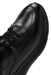 Sneaker in pelle nera con upper testurizzato, punta rotonda, colletto imbottito e lacci neri. La suola è in gomma con un motivo rigato per migliorare la presa.
