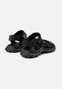 Sorte svarte sandaler med holdbare nylonremmer, justerbare lukkinger og teksturerte gummisåler med et robust mønster.