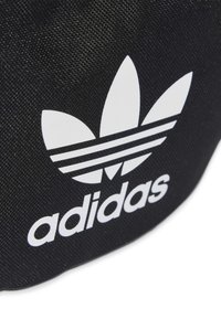Svart texturerad tygytan med en vit Adidas trefoil-logotyp och varumärket "adidas" i små bokstäver.