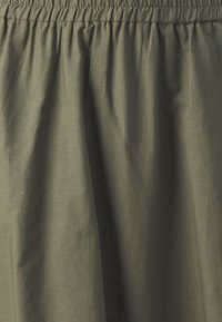 Olivgrüner Baumwollrock mit elastischem Bund, der eine glatte Textur und ein gerafftes Design aufweist, das eine entspannte Silhouette schafft.