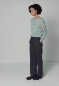 Jasnoszary sweter, luźny fason, okrągły dekolt; antracytowe spodnie o szerokich nogawkach, dopasowane, z wysokim stanem; czarne buty, gładka faktura.