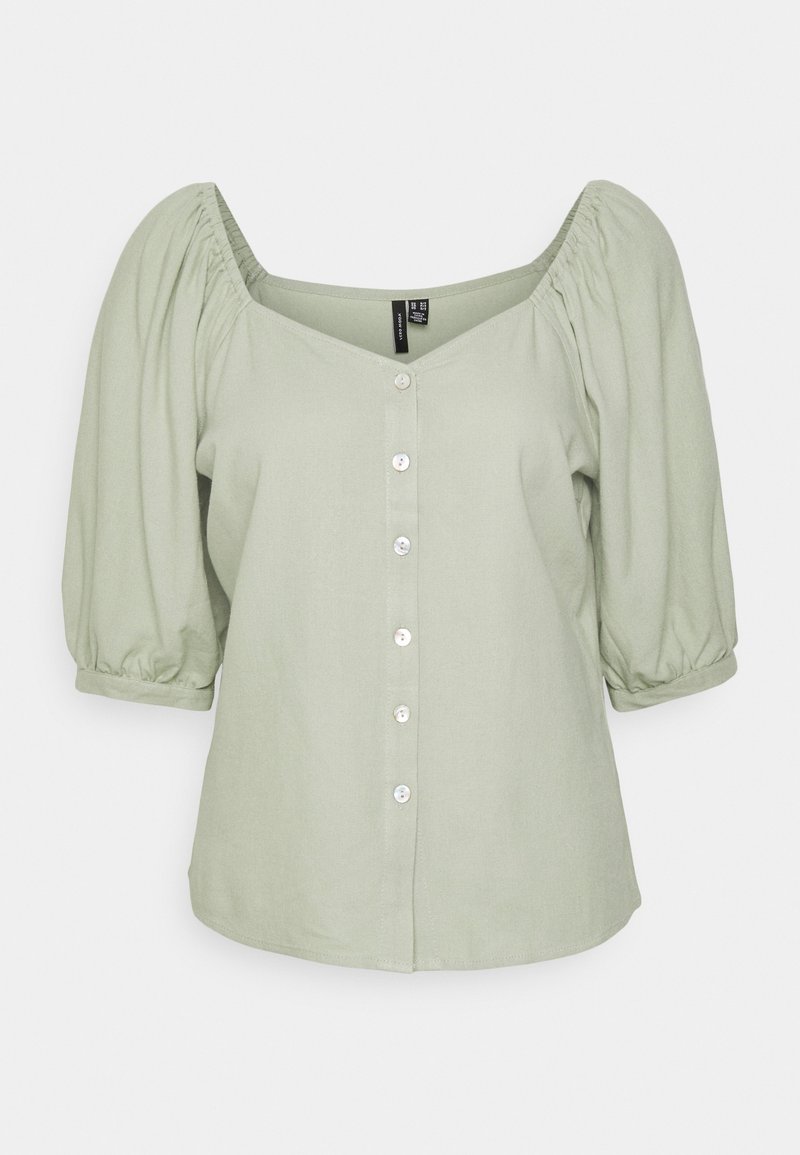 Blouse vert clair avec manches bouffantes mi-longues jusqu'aux coudes, fermeture à boutons sur le devant et large encolure carrée.