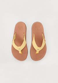 Flip-flops galbene cu o talpă din cauciuc texturat de culoare maro și curele din piele galbenă, dotate cu un logo distinctiv și un design tip thong.