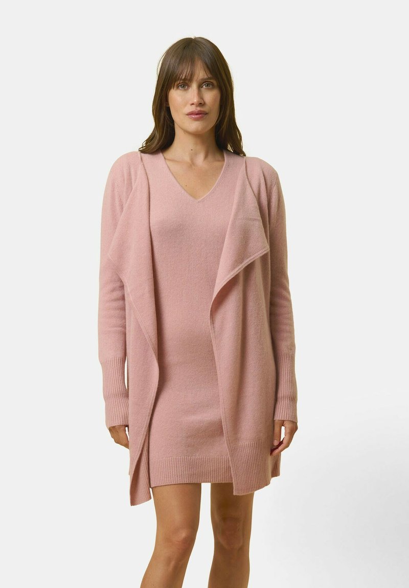 Ljusrosa stickad cardigan med öppen front, långa ärmar och ribbade manschetter, lagrad över en matchande figurnära klänning med V-ringning.