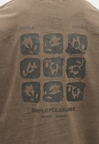 Καφέ ύφασμα με μαύρα μπλοκ τέχνης που παρουσιάζουν αφηρημένα σχήματα φύλλων, με ετικέτες "ΕΙΣΠΝΟΗ" και "ΕΚΠΝΟΗ", και κείμενο "ΑΠΛΕΣ ΑΠΟΛΑΥΣΕΙΣ SAMSOE SAMSOE."