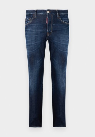 Jean en denim bleu foncé coupe slim avec détails délavés, fermeture avant par boutons et fermeture éclair, cinq poches, et une étiquette de marque rouge.